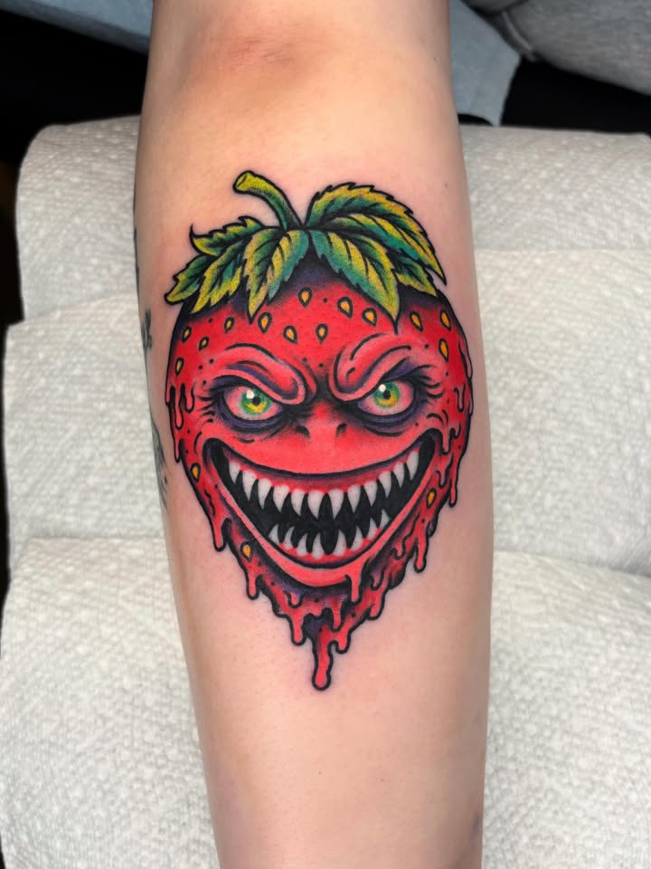 Evil grinning strawberry tattoo